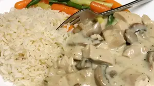 German chicken fricassee with mushrooms in a creamy white sauce, served with rice and mixed vegetables.