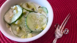 Cucumber dill pickle salad in white bowl with fork on the side