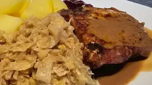 Plate of German creamed cabbage served with pork chop, gravy, and boiled potatoes.