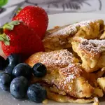 Kaiserschmarrn, or “Emperor’s Mess,” is a fluffy, caramelized pancake torn into pieces and dusted with sugar—a royally delicious treat!