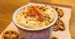 Bowl of Obatzda cheese spread topped with paprika and chives, served with pretzels.