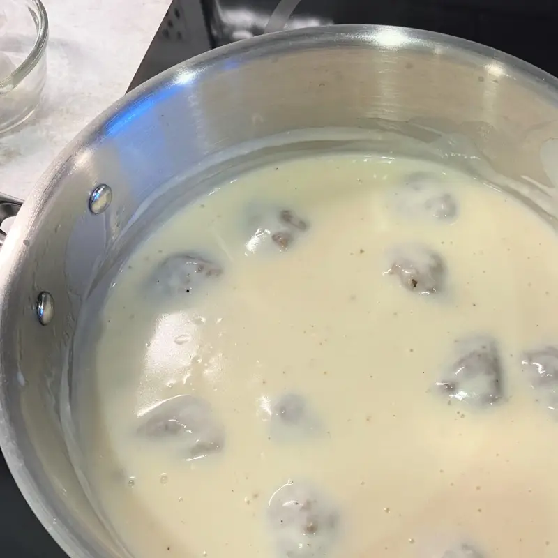 Steamed vegan seitan meatballs simmering in a creamy sauce in a skillet.