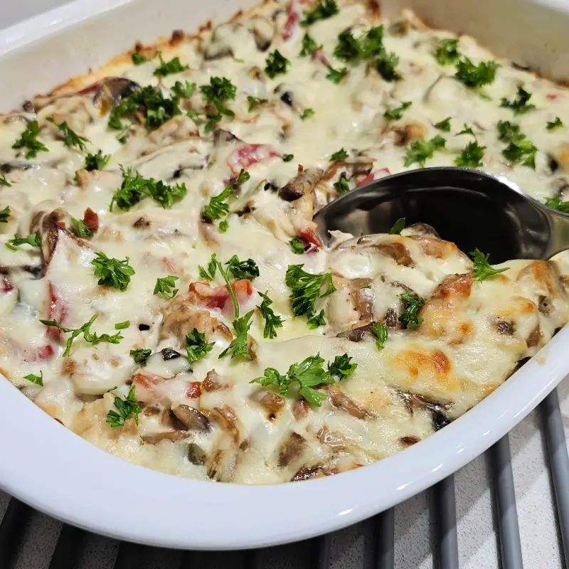 Baked creamy chicken spätzle casserole with mushrooms and melted cheese, sprinkled with parsley