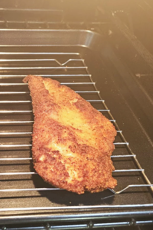 Fried chicken schnitzel on a wire rack in a warm oven