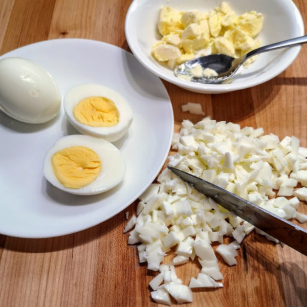Remove the yolks from the hard-boiled eggs and chop the egg whites.