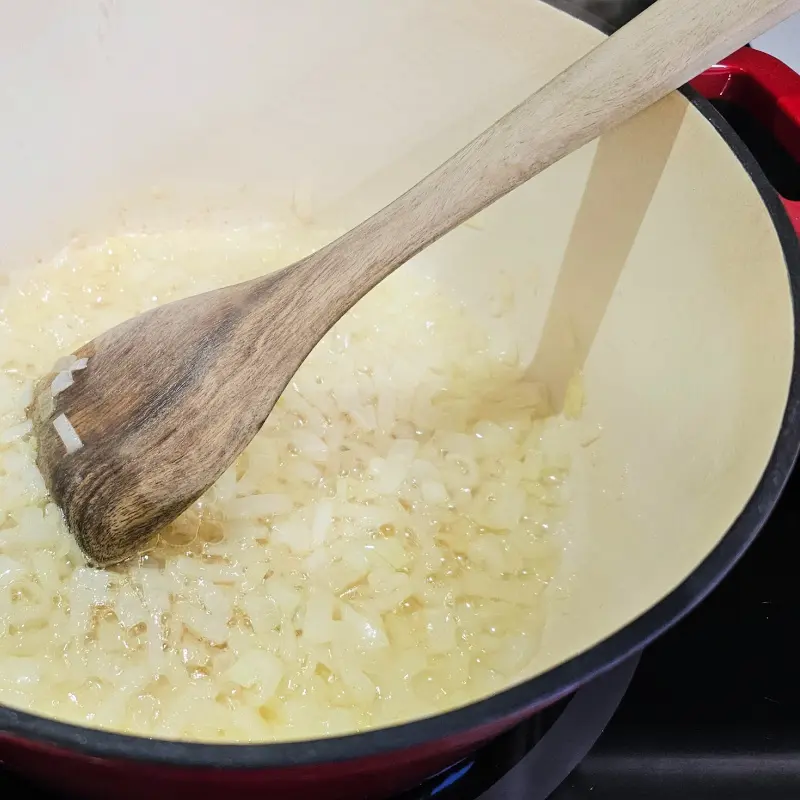 Diced onions cooking gently in butter inside a red Dutch oven. Diced onions cooking gently in butter inside a red Dutch oven.