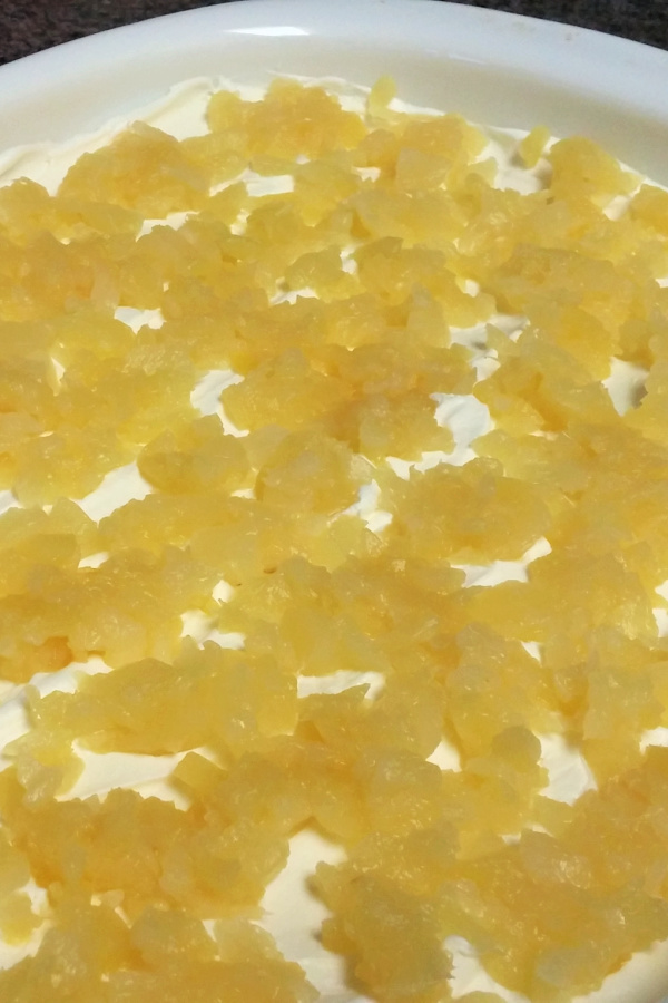 Crushed pineapple scattered over the whipped topping on a soda cracker icebox cake.