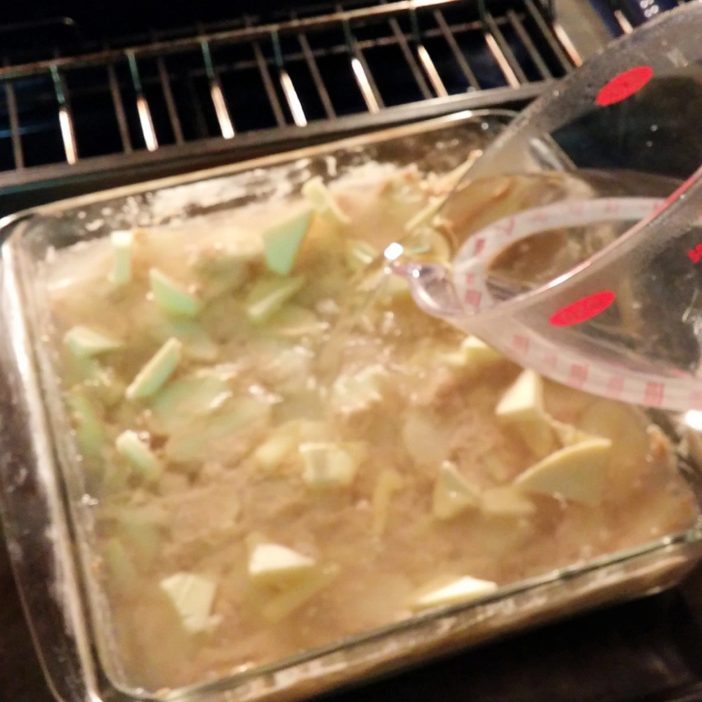 Adding water to apple pudding cake in the oven