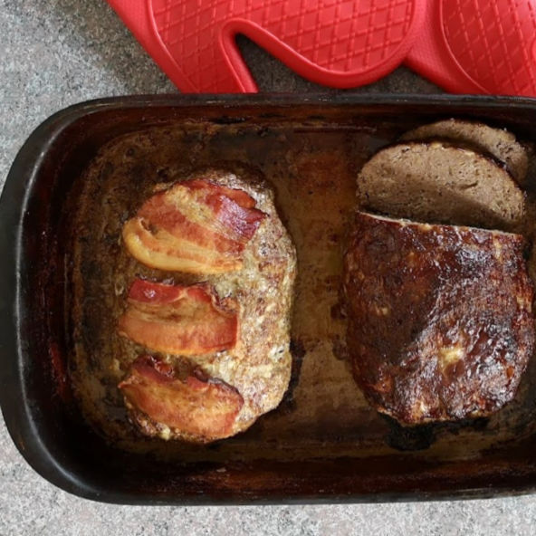Finished meatloaves in pan, one with crispy bacon, one glazed with BBQ sauce.