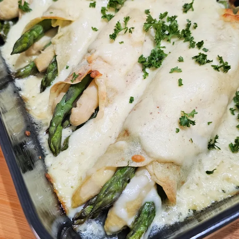 Baked asparagus and ham crêpes casserole garnished with parsley Baked asparagus and ham crêpes casserole garnished with parsley