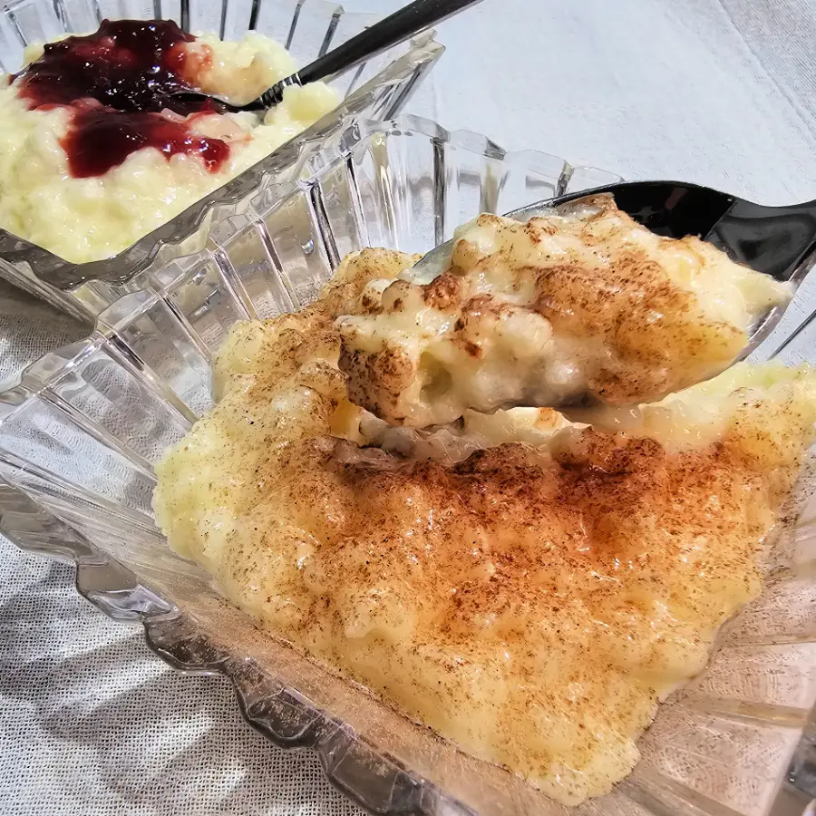 Spoonful of baked Milchreis topped with cinnamon, with fruit compote on the side