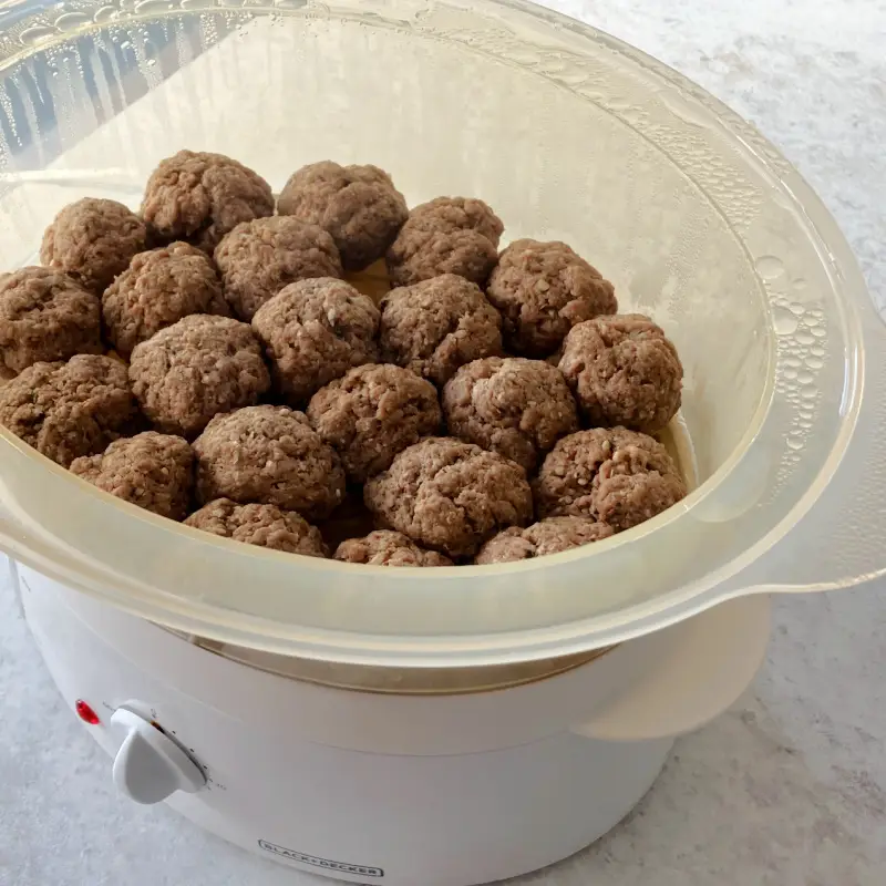 Vegan seitan meatballs steaming in a countertop steamer insert.