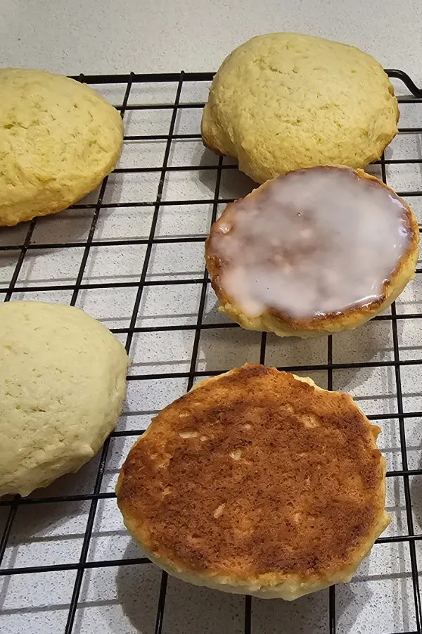 Baked Amerikaner on a cooling rack showing domed tops, one iced flat side and one golden-brown flat bottom