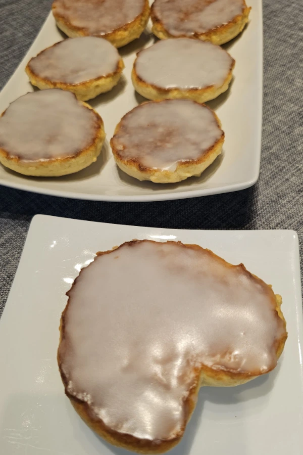 Platter of iced Amerikaner, German iced cake cookies, with a heart-shaped Amerikaner on a small white plate