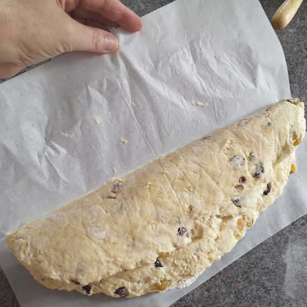 Pull back parchment paper from Stollen dough Pull back parchment paper from Stollen dough
