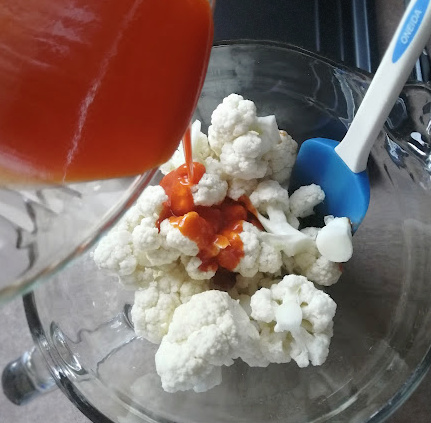 Pour wing sauce and melted butter mixture over cauliflower pieces Pour wing sauce and melted butter mixture over cauliflower pieces