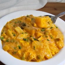 Creamy German chicken and potato soup in a white bowl, with a spoon lifting a potato cube
