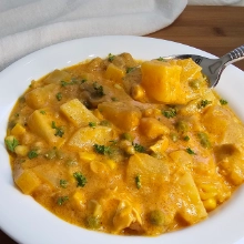 Creamy German chicken and potato soup in a white bowl, with a fork lifting a potato cube