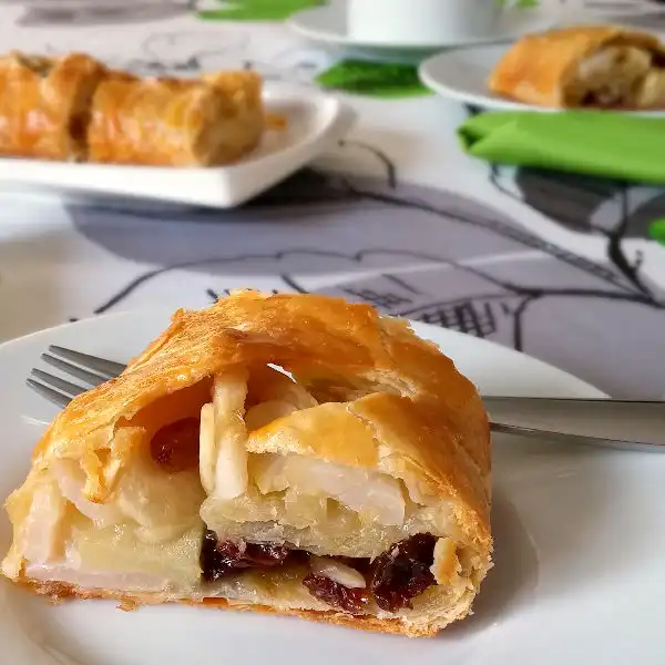 Apple strudel made with puff pastry and filled with sliced apples and raisins