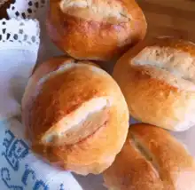 Golden homemade German bread rolls on a wooden board.
