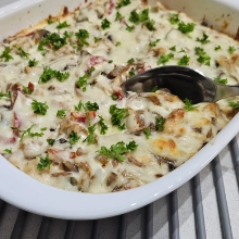 Baked chicken spätzle casserole in a white dish with melted cheese, mushrooms and red peppers browned at the edges
