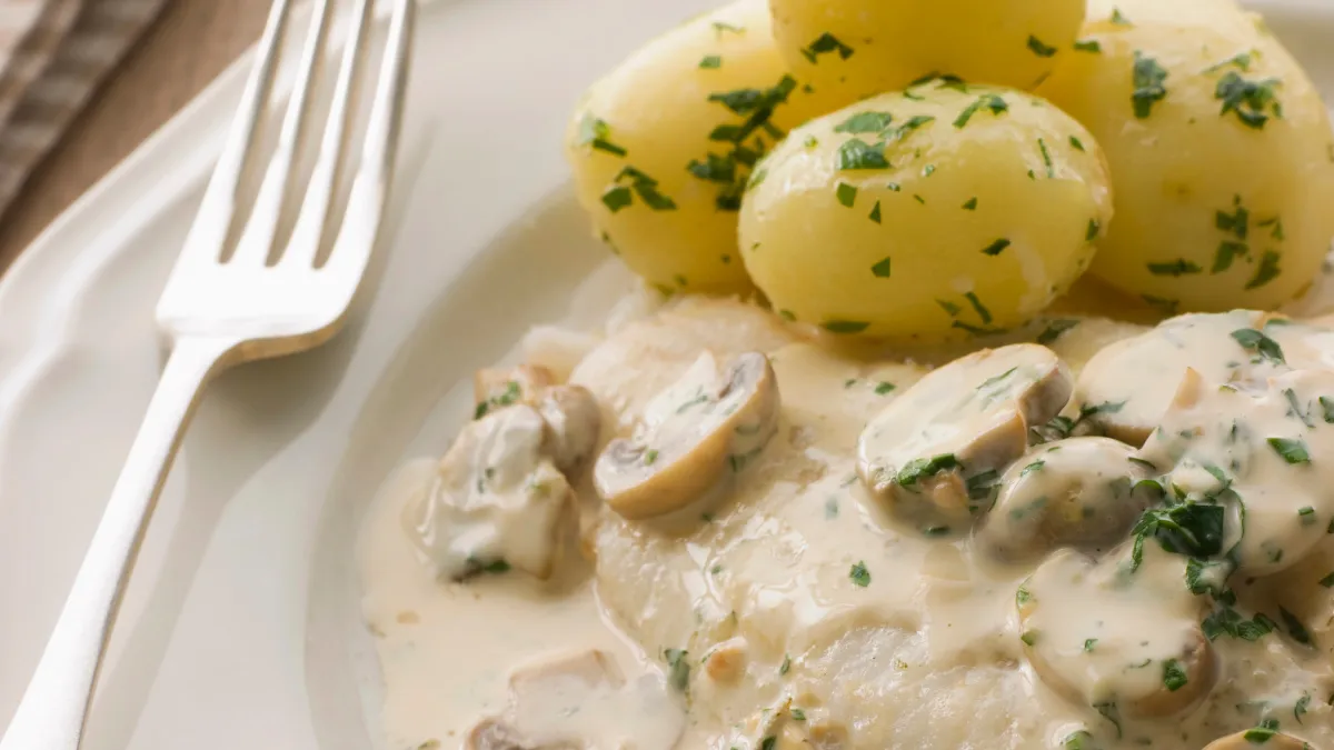 fricasseed fish on white plate with potatoes