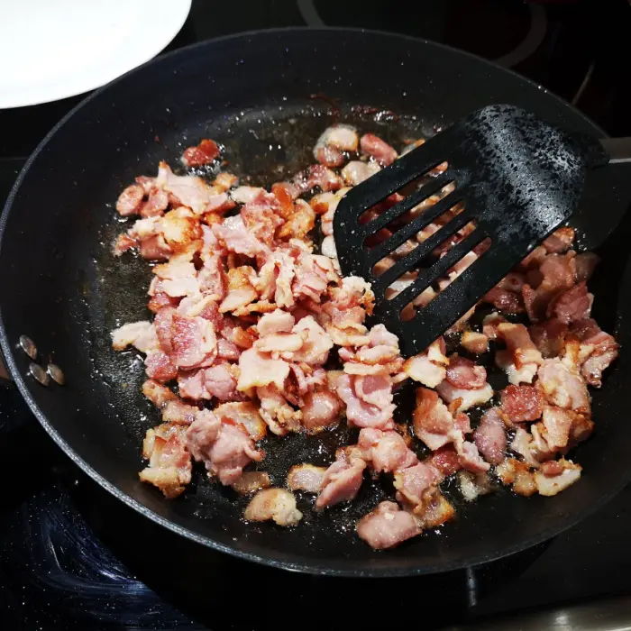 frying diced bacon in fry pan frying diced bacon in fry pan
