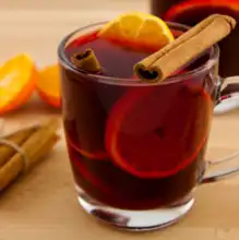 Glass of mulled wine garnished with orange slices and cinnamon stick