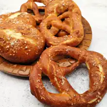 Baked soft pretzels and pretzel buns with a golden crust on a white plate