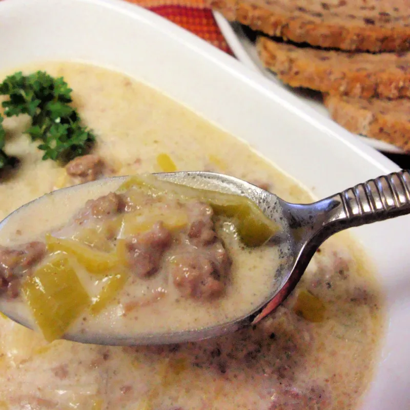 Spoonful of hearty leek and meat soup in a creamy broth with fresh parsley