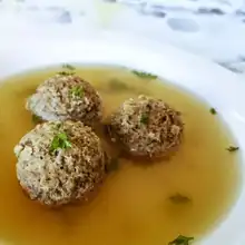 Three liver dumplings in a clear broth garnished with herbs