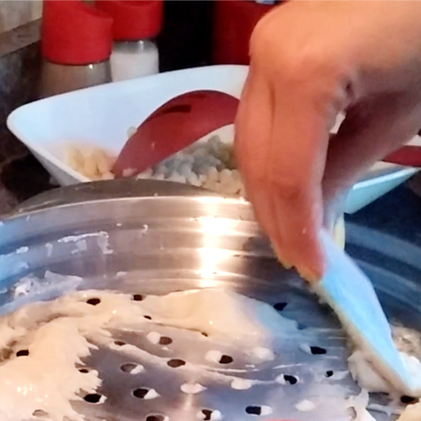 Use a Spätzle lid and scrapper to push dough through holes Use a Spätzle lid and scrapper to push dough through holes