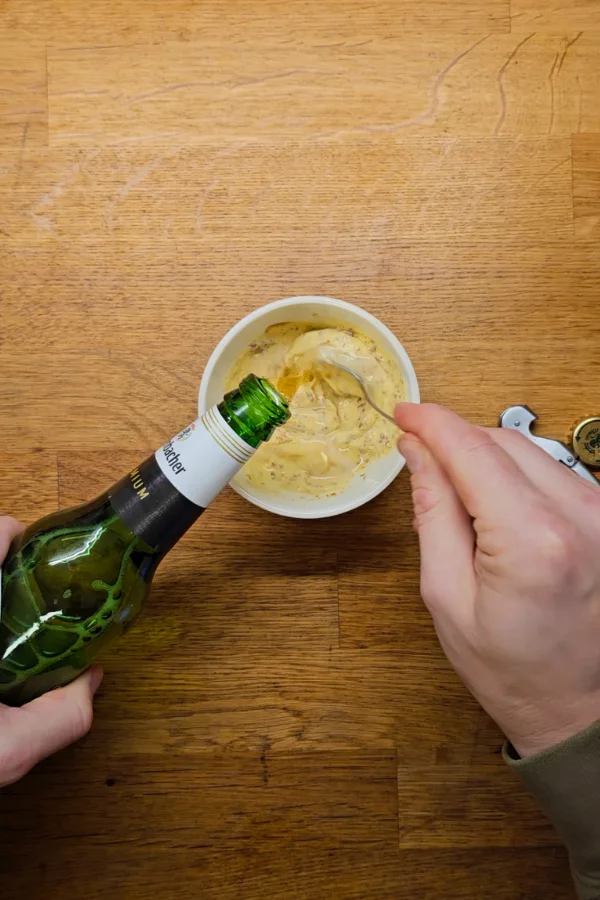 Making the beer mustard sauce Adding German beer to a homemade mustard sauce while preparing pork schnitzel sliders.