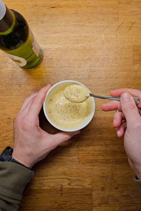 Finishing the beer mustard sauce Bowl of German beer mustard sauce for pork schnitzel sliders, stirred with a spoon.