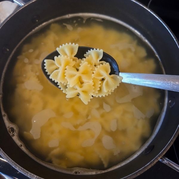 Farfalle pasta boiling in a pot of water for dill pickle pasta salad recipe