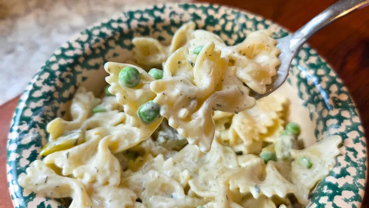 Close-up of creamy dill pickle pasta salad with bowtie pasta and peas