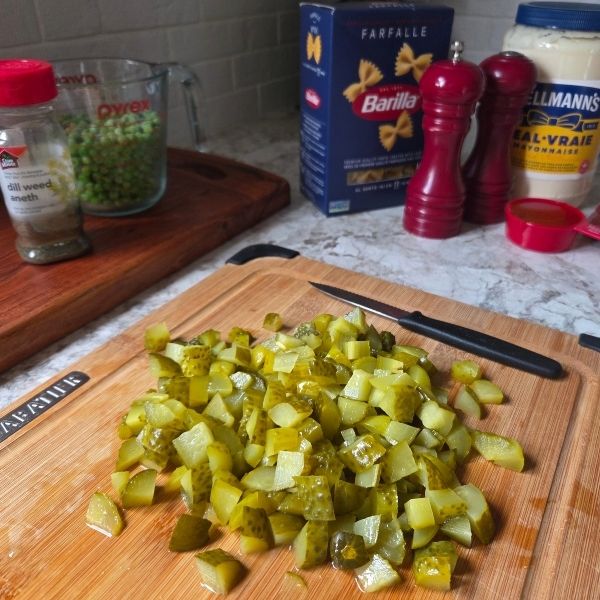 Chopped pickles and ingredients prepared for creamy dill pickle pasta salad recipe