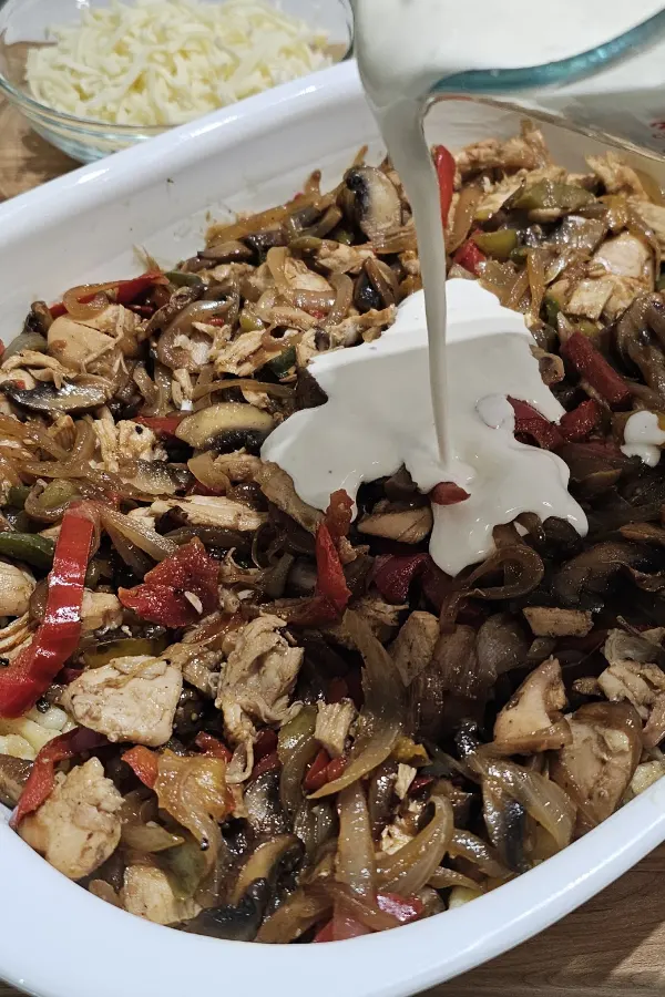 Cream and sour cream mixture poured over chicken and vegetables in a casserole dish