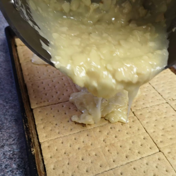 Pouring nut mixture over graham crackers.