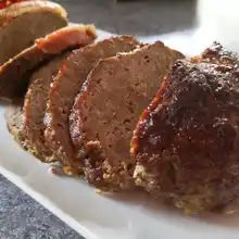 Sliced traditional German meatloaf arranged on a white platter.