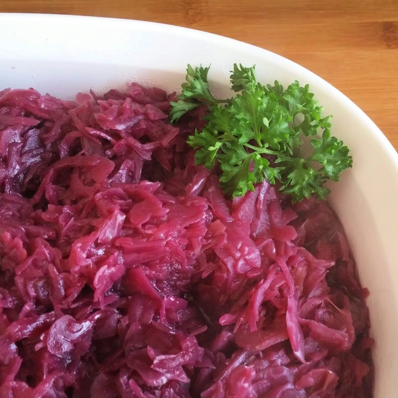 A white bowl of vibrantly red-colored German red cabbage with parsley