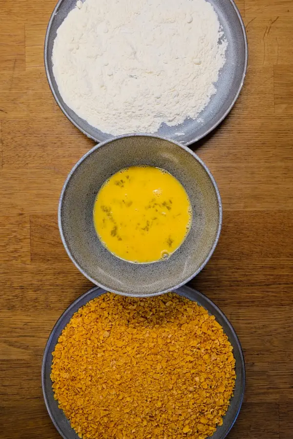 Coating the pork Flour, egg wash, and crushed breadcrumb coating arranged for dredging pork schnitzel cutlets.