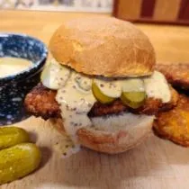 Crispy pork schnitzel sliders on a bun topped with creamy beer mustard sauce and pickles