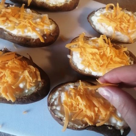 Sprinkling my favorite cheese on my air fryer twice-baked potatoes. Yum! Get ready for some ooey-gooey goodness. Sprinkling my favorite cheese on my air fryer twice-baked potatoes. Yum! Get ready for some ooey-gooey goodness.