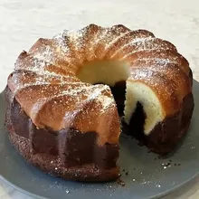 Sliced vegan German marble cake on a plate dusted with powdered sugar