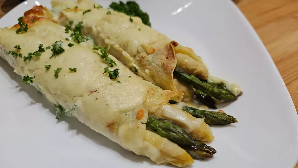 Baked asparagus and ham crêpes casserole garnished with parsley