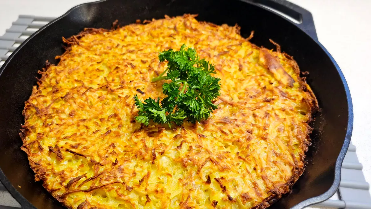 Kartoffelpuffer aus dem Ofen (baked German potato pancake casserole) baked in a cast-iron skillet with a crispy golden top and parsley garnish