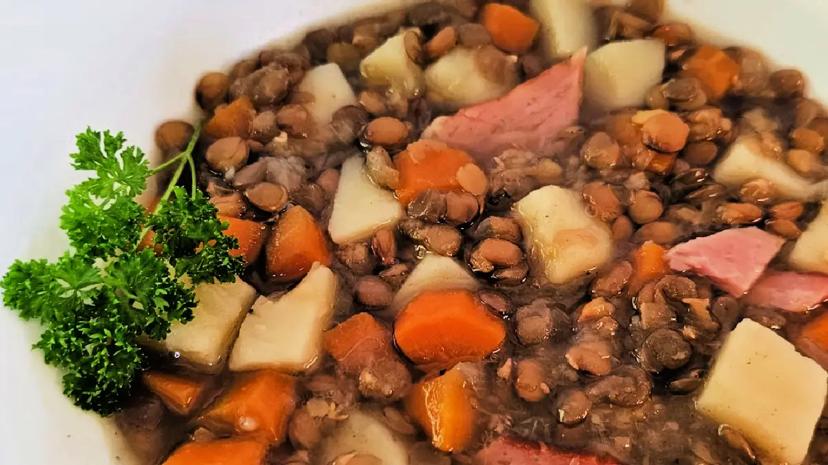 lentil soup with ham served in a white bowl